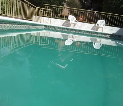 a swimming pool with chairs and blue water at Cabañas La Morada de Tanti in Tanti
