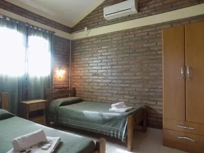 a room with two beds and a brick wall at Cabañas La Morada de Tanti in Tanti