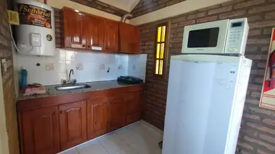 a kitchen with a microwave and a refrigerator at Cabañas La Morada de Tanti in Tanti