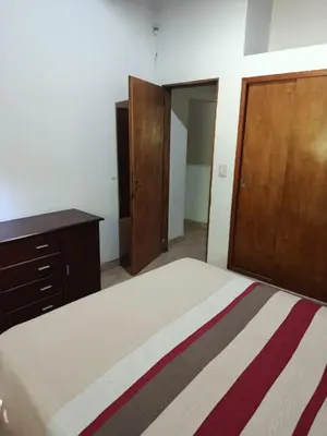 a bedroom with a bed and a wooden cabinet at Das Kleine Nest in Villa General Belgrano