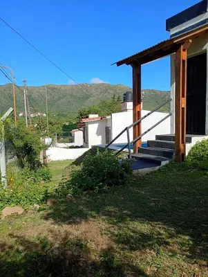 a house with stairs and a porch with mountains in the background at Casa Serrana Punilla in Santa María