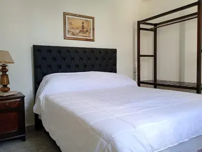 a bedroom with a large white bed with a black headboard at Casa Serrana Punilla in Santa María
