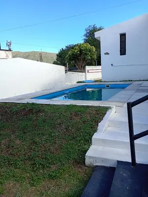 a swimming pool next to a white house at Casa Serrana Punilla in Santa María