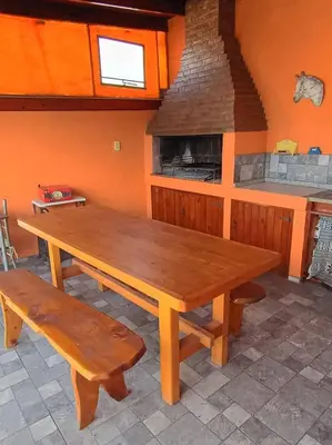 a wooden table and benches in a room with a stove at Casa Serrana Punilla in Santa María