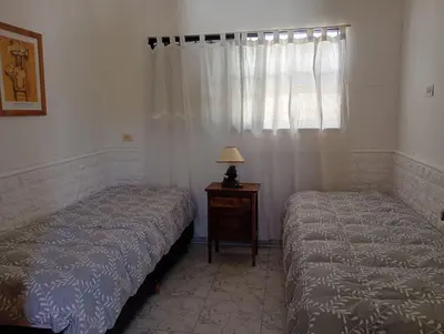 two beds in a bedroom with a table and a window at Casa Serrana Punilla in Santa María