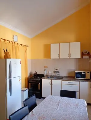 a kitchen with a white refrigerator and a table with chairs at Casa Serrana Punilla in Santa María