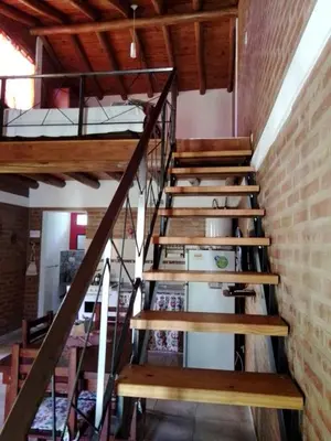 a set of wooden stairs in a room with a brick wall at Aguaribay Cabañas in Arroyo de Los Patos
