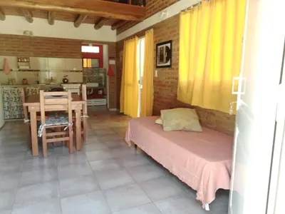 a bedroom with a bed and a table and a kitchen at Aguaribay Cabañas in Arroyo de Los Patos