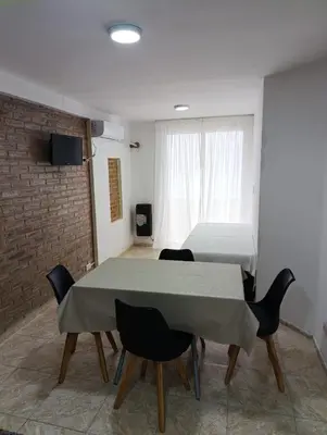 a room with a table and chairs and a bed at Dpto Centro de Carlos Paz - Avellana in Villa Carlos Paz