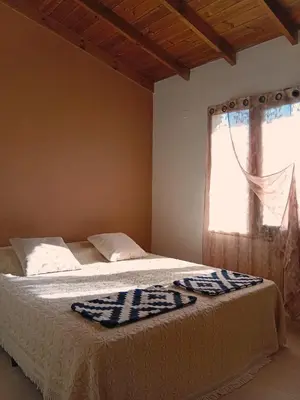 a bedroom with a bed with a window with a blanket at Suspiro Serrano in Villa General Belgrano