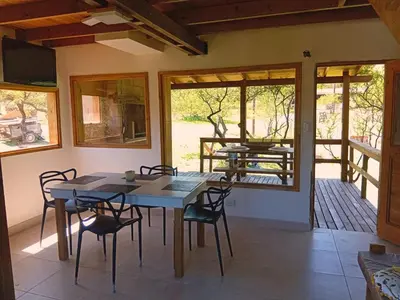 a dining room with a table and chairs on a porch at Suspiro Serrano in Villa General Belgrano
