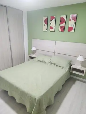 a bedroom with a large bed and three paintings on the wall at Traslasierra Champaquí Deptos in Villa Dolores