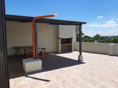 a patio with a table and a grill on a roof at Traslasierra Champaquí Deptos in Villa Dolores