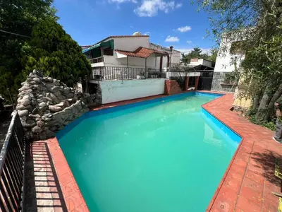 a large blue swimming pool in front of a house at noreservar in Villa Carlos Paz