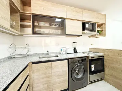 a kitchen with a washing machine and a microwave at PASEO QUATTRO Alquileres in Villa Carlos Paz