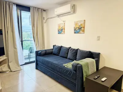 a blue couch in a living room with a window at PASEO QUATTRO Alquileres in Villa Carlos Paz