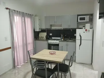 a kitchen with a table and a white refrigerator at Miralejos I Carlos Paz in Villa Carlos Paz