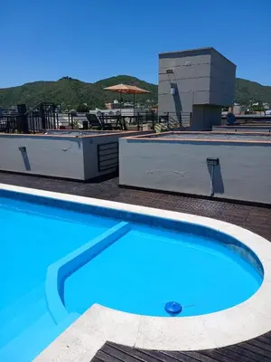 a large blue swimming pool next to a building at Miralejos I Carlos Paz in Villa Carlos Paz