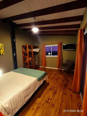 a bedroom with a bed and a chair and a window at Cabaña Ali in Villa Rumipal