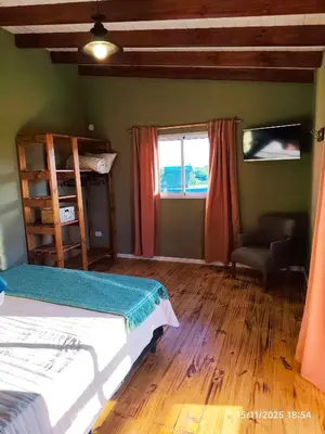 a bedroom with a bed and a chair and a window at Cabaña Ali in Villa Rumipal