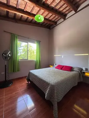 a bedroom with a bed with green curtains and a window at Las Tole - Potrero de Garay in La Estancia