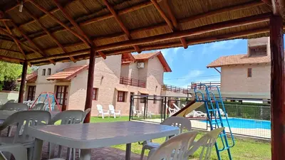 a patio with tables and chairs and a playground at Complejo Terrazas de Cynthia in Mina Clavero
