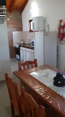 a kitchen with a table with chairs and a refrigerator at Complejo Terrazas de Cynthia in Mina Clavero