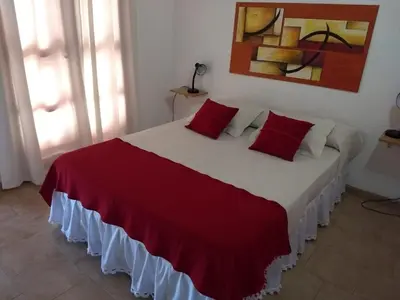 a bedroom with a large bed with red pillows at Complejo Terrazas de Cynthia in Mina Clavero