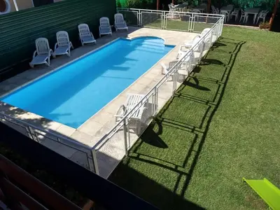 a swimming pool with chairs and a fence around it at Complejo Terrazas de Cynthia in Mina Clavero