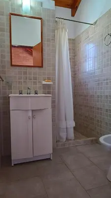 a bathroom with a sink and a shower with a mirror at Complejo Terrazas de Cynthia in Mina Clavero