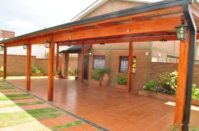 a wooden pergola in front of a house at Complejo Carola in Villa Carlos Paz