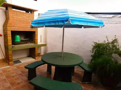 a picnic table with an umbrella and two benches at Complejo Carola in Villa Carlos Paz