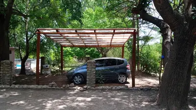 a small car parked under a wooden structure next to a tree at Casa Megafó no in Las Rabonas