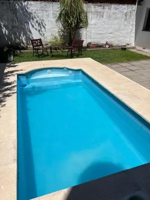 a blue swimming pool in a yard with two chairs at Casa céntrica in Villa Carlos Paz