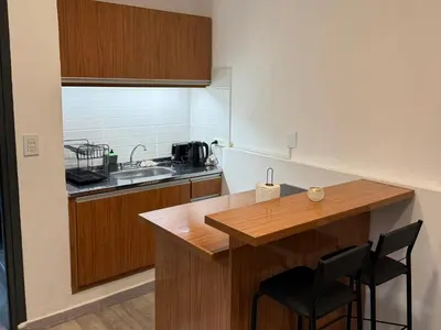 a small kitchen with a wooden counter and a sink at Apart's Sobremonte - Deptos Modernos in Rio Cuarto