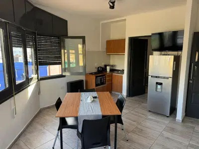 a kitchen with a dining table and a refrigerator at Apart's Sobremonte - Deptos Modernos in Rio Cuarto