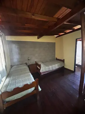 two beds in a room with wooden floors at Cabañas EzeNic in Cavalango