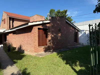 a brick house with a gate in the yard at Casa Arroyo in Villa Carlos Paz
