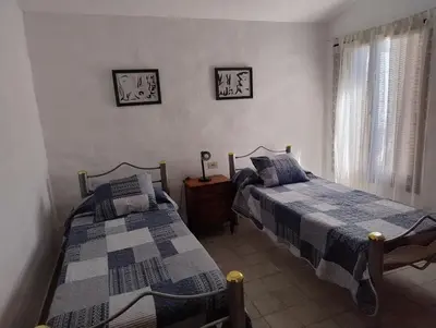 a bedroom with two beds and a table and a window at Casa Arroyo in Villa Carlos Paz