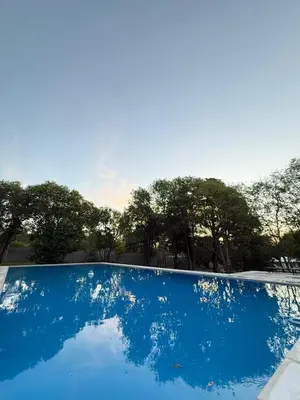 a blue swimming pool with trees in the background at Hosteria Champaqui in Los Hornillos