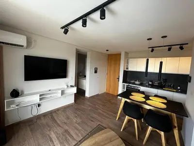 a living room with a table with chairs and a flat screen tv at Hermoso Departamento en zona Quality Espacio, Hospital Privado Universitario de Córdoba in Cordoba