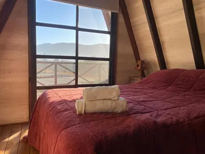 a bedroom with a red bed with a large window at Alpinas del Valle in Santa Rosa de Calamuchita