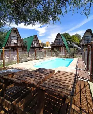 a pool with a wooden bench next to a house at Alpinas del Valle in Santa Rosa de Calamuchita