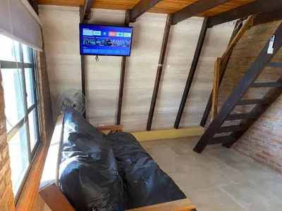 a room with a couch and a tv on a wall at Alpinas del Valle in Santa Rosa de Calamuchita