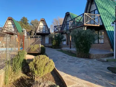 a house with a green roof and some bushes at Alpinas del Valle in Santa Rosa de Calamuchita