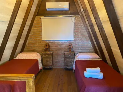 a attic room with two beds and a window at Alpinas del Valle in Santa Rosa de Calamuchita