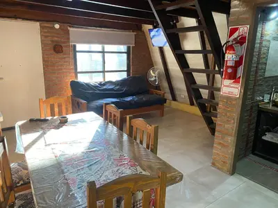 a dining room with a table and a living room at Alpinas del Valle in Santa Rosa de Calamuchita