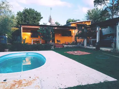 a house with a swimming pool in front of a yard at Casa colibrí in Tanti