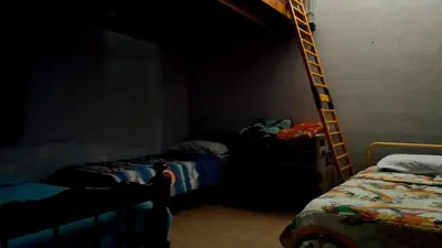 a dark room with two bunk beds and a ladder at Casa colibrí in Tanti