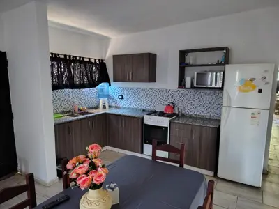 a kitchen with a table and a white refrigerator at Cabaña papáviejo in Villa de Las Rosas